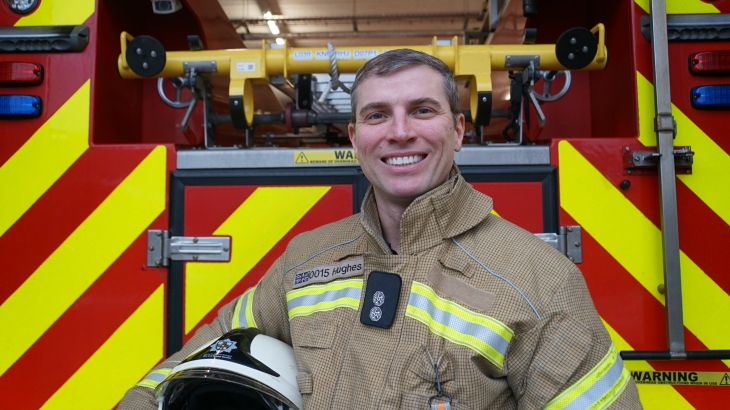 On-call Watch Manager Kieran Hughes standing in front of a fire engine. 